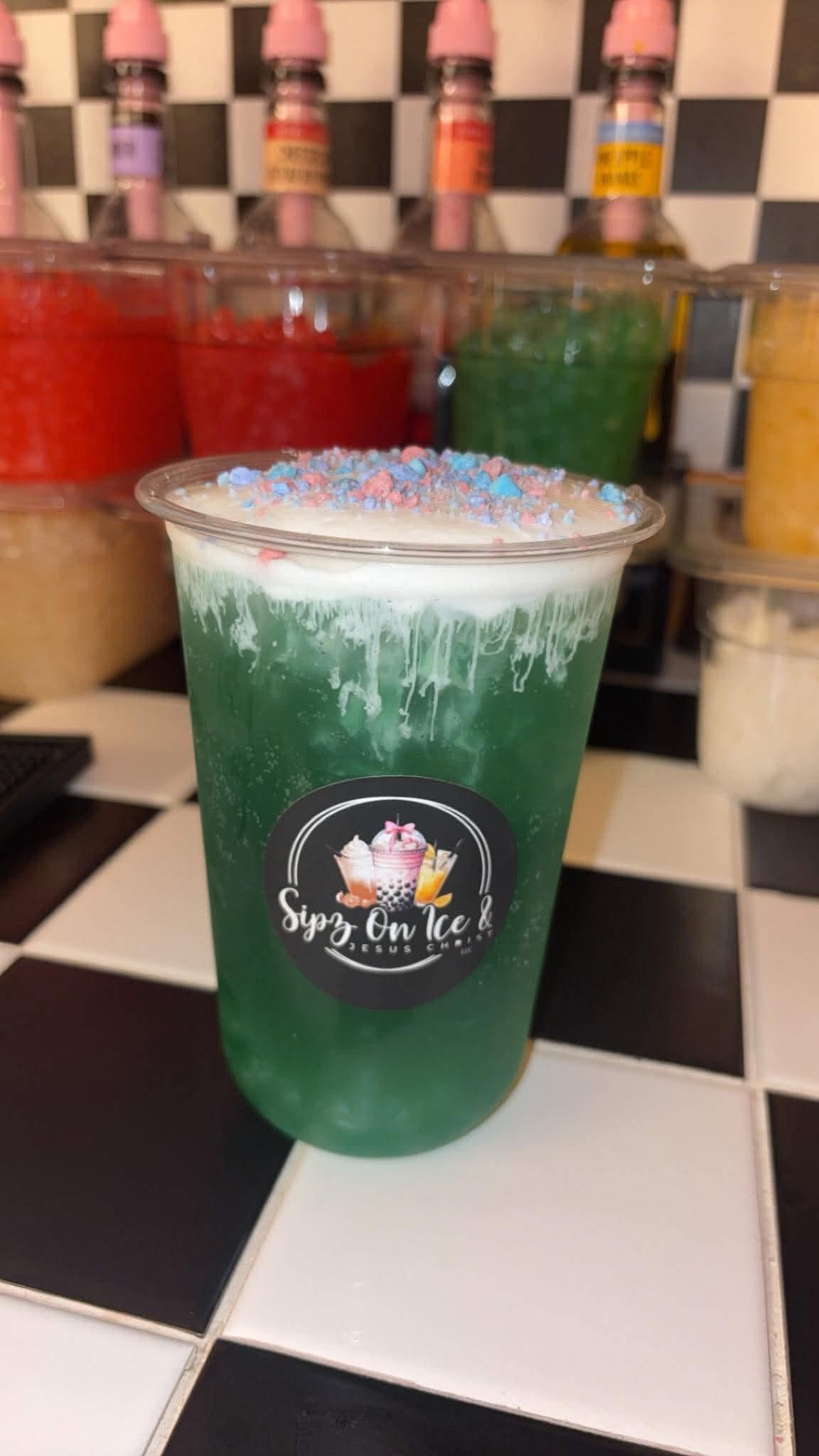 Green custom drink with crushed candy topping on the checkered counter