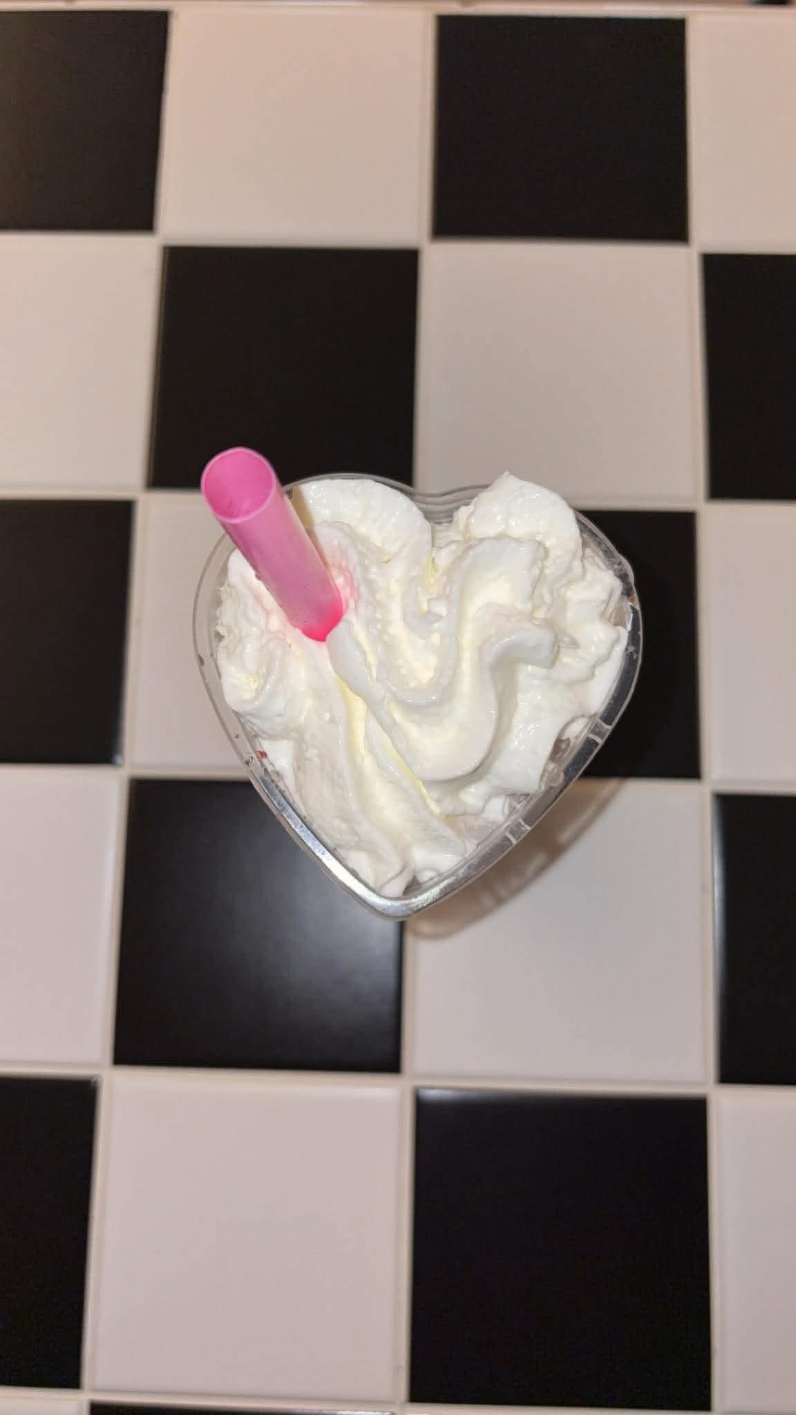 Heart-shaped cup filled with whipped cream on the checkered counter
